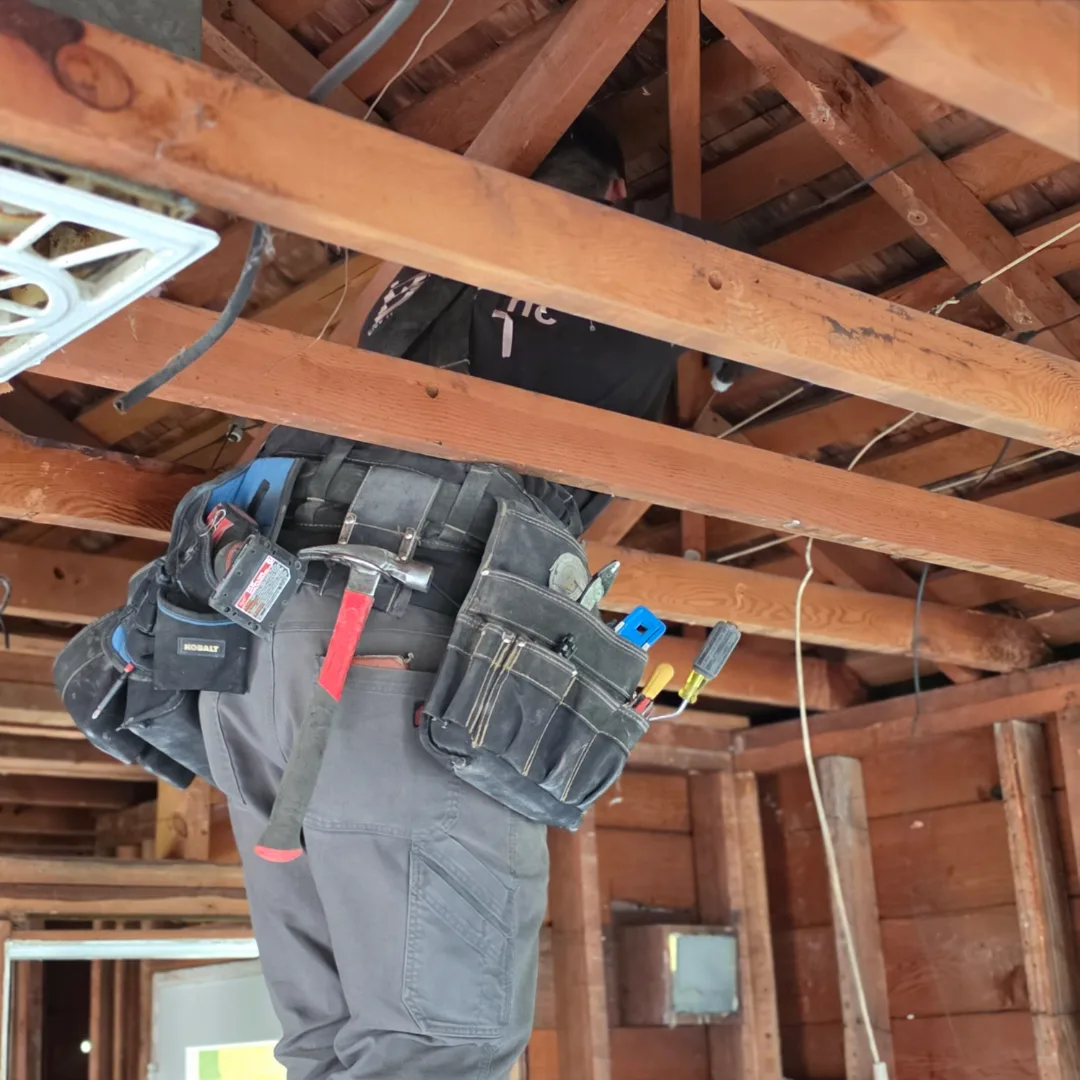 Electrician working in open framing during a Seattle older home rewiring project