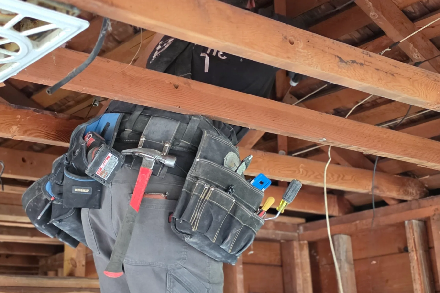 Benchmark electrician replacing old wiring while a remodel ceiling is open