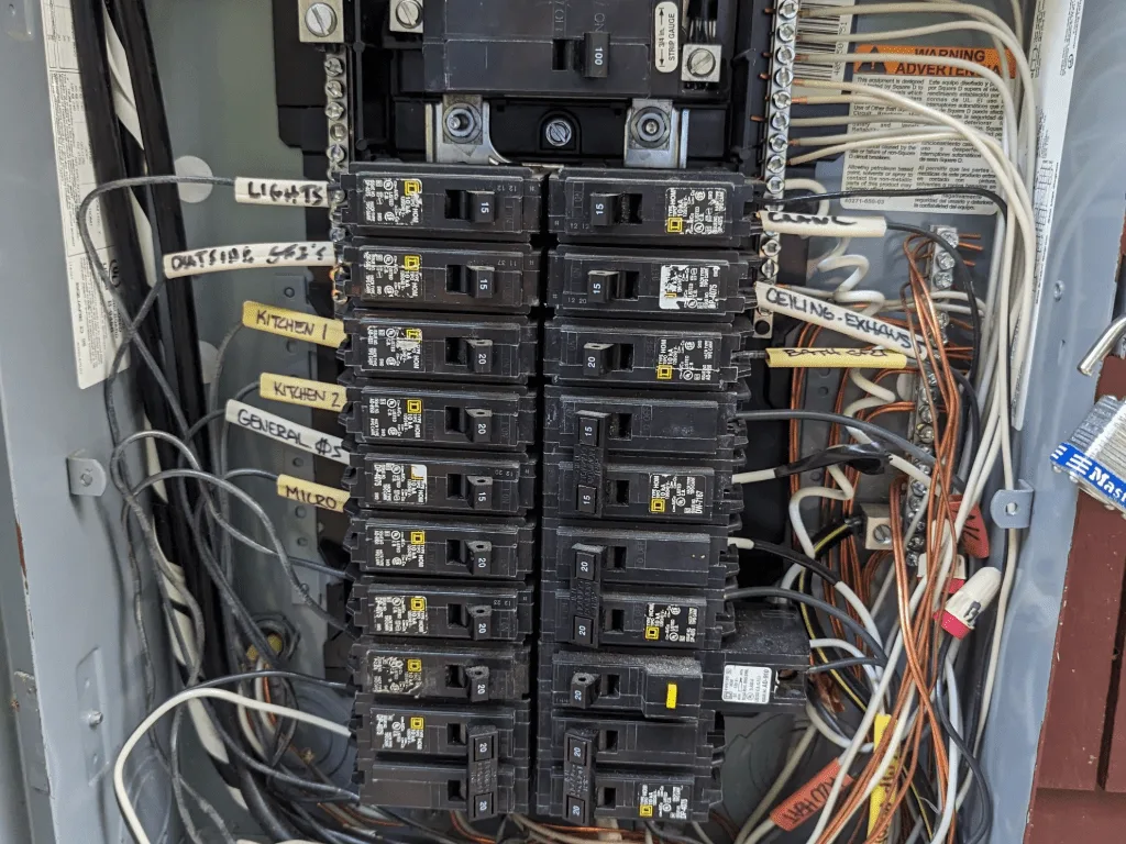 Open electrical panel with branch-circuit labels and wiring